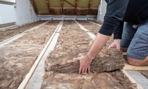 Das Foto zeigt ein Handwerker beim Dämmen der obersten Geschossdecke