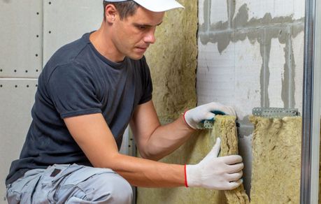 Das Foto zeigt einen Handwerker beim Dämmen einer Innenwand