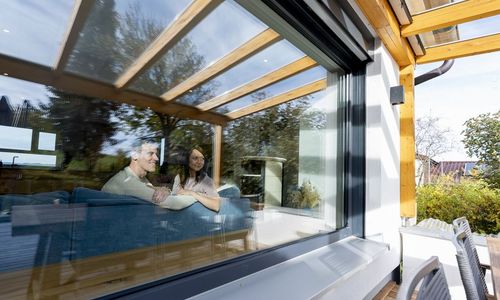 Das Foto zeigt ein Ehepaar am Fenster