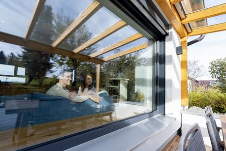 Das Foto zeigt ein Ehepaar am Fenster