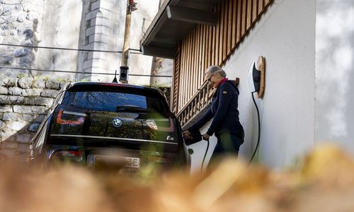 Das Bild zeigt eine Frau beim Laden eines E-Autos
