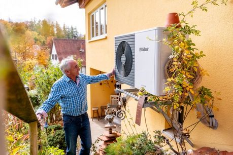 Wärmepumpe mit Person draußen vor dem Haus