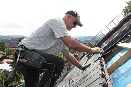 Handwerker deckt Dach ein