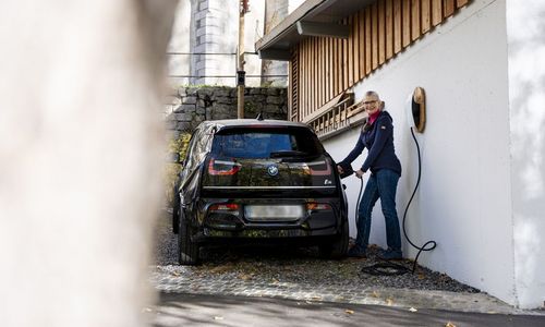 Das Bild zeigt eine Frau mit einem gebrauchten E-Auto