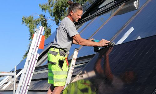Das Foto zeigt einen Handwerker bei der Montag eines PV-Moduls