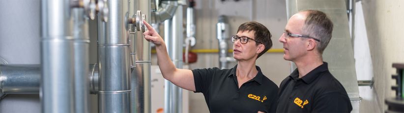 eza!-kommunales-energiemanagement Auf dem Bild zu sehen sind zwei Mitarbeiter des kommunalen Energiemanagements, Birgit Stingl und Rainer Moll, die gerade dabei sind, eine Heizungsanlage zu optimieren.